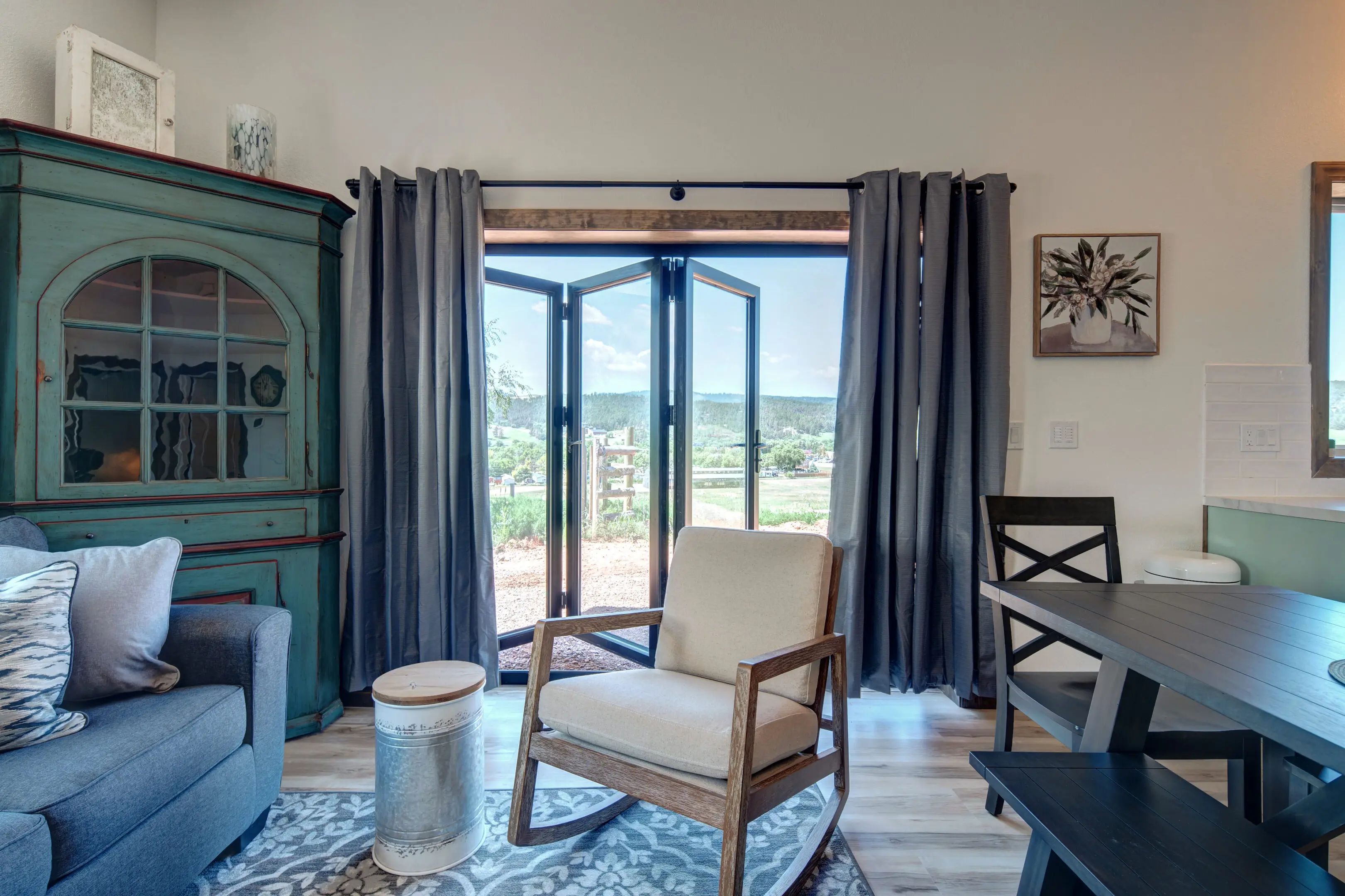 A living room with blue curtains and a rocking chair.