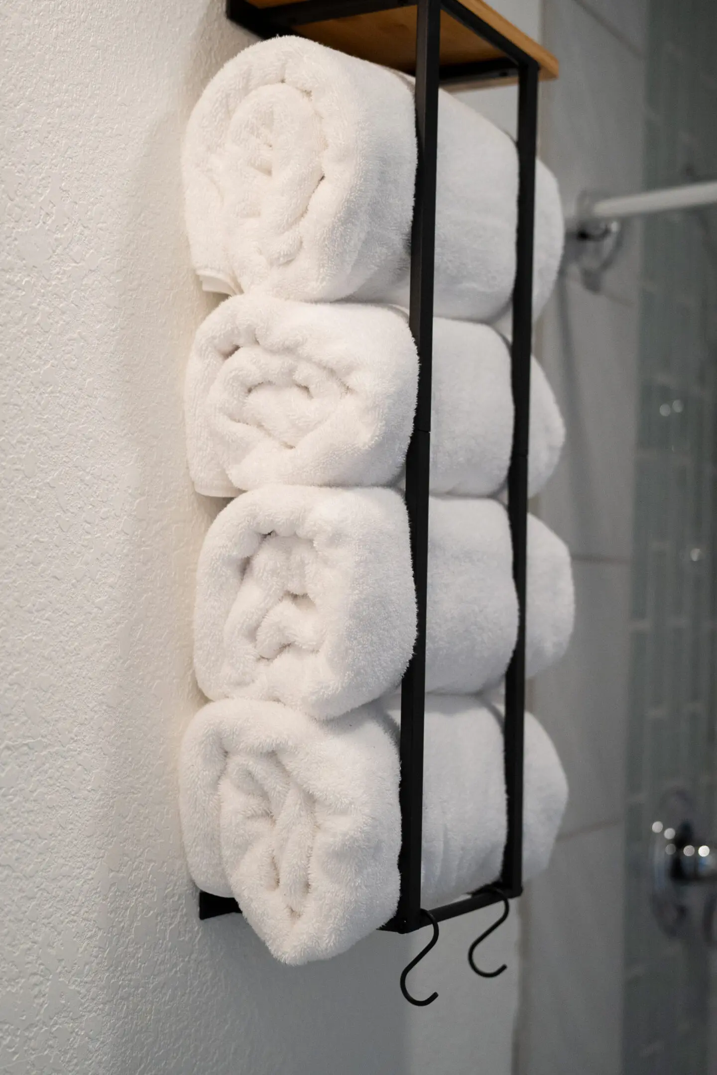 A rack of rolled up towels in front of the shower.