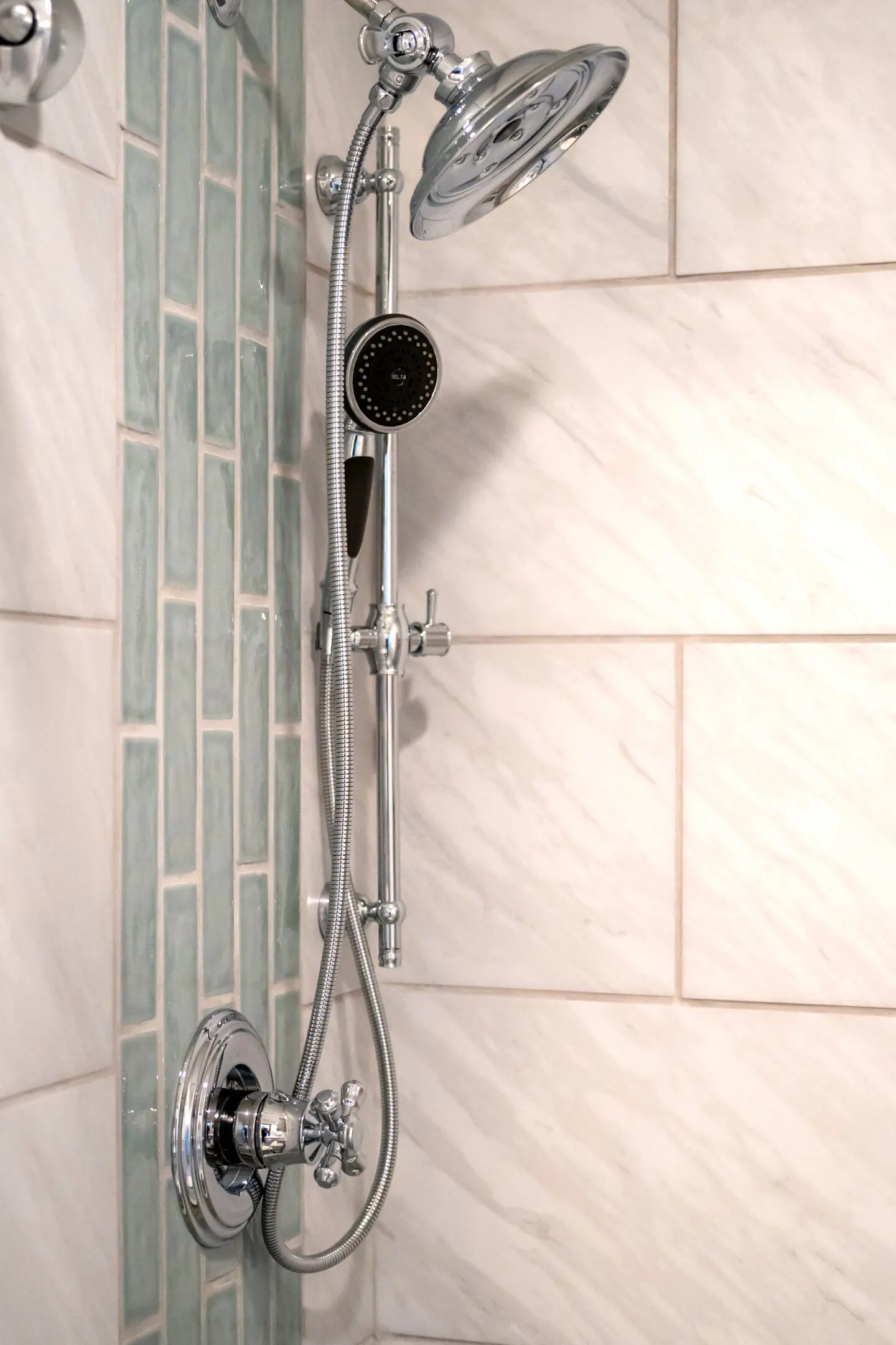 A shower head with a glass tile wall.
