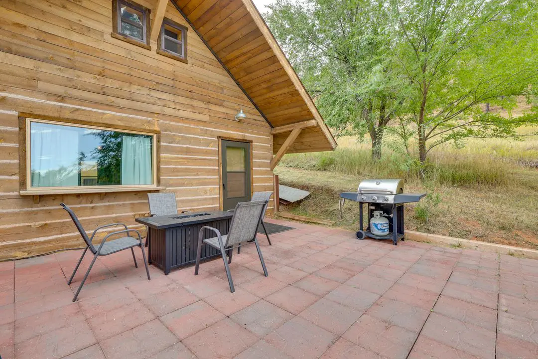 A patio with chairs and table outside of cabin.