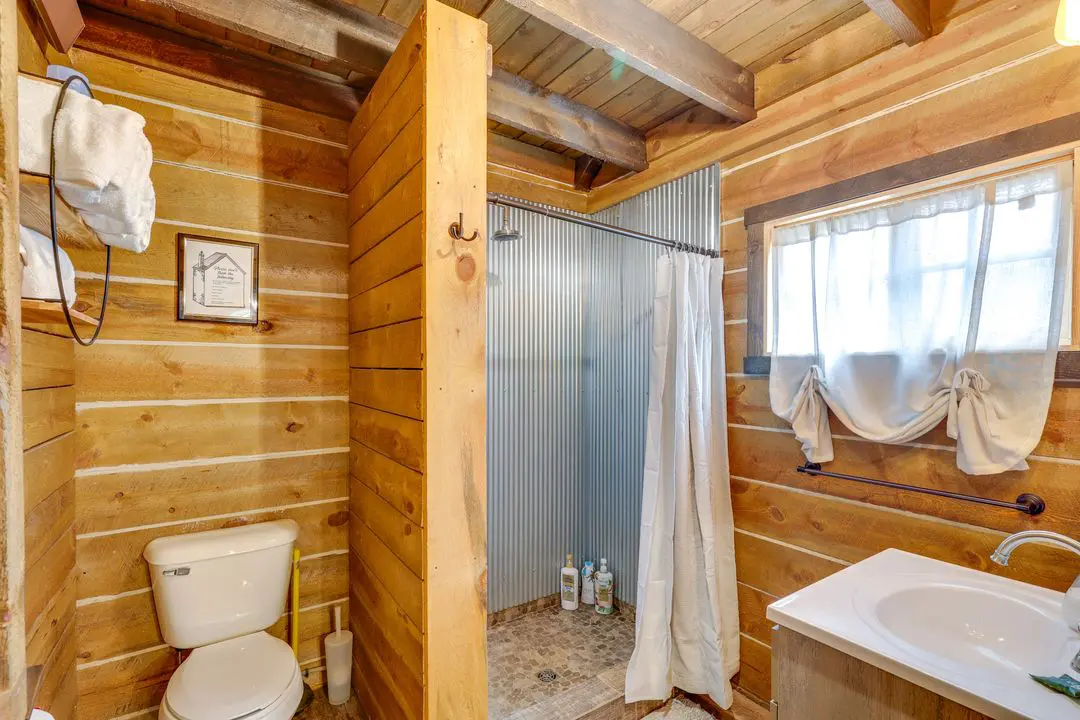 A bathroom with wood paneling and white fixtures.