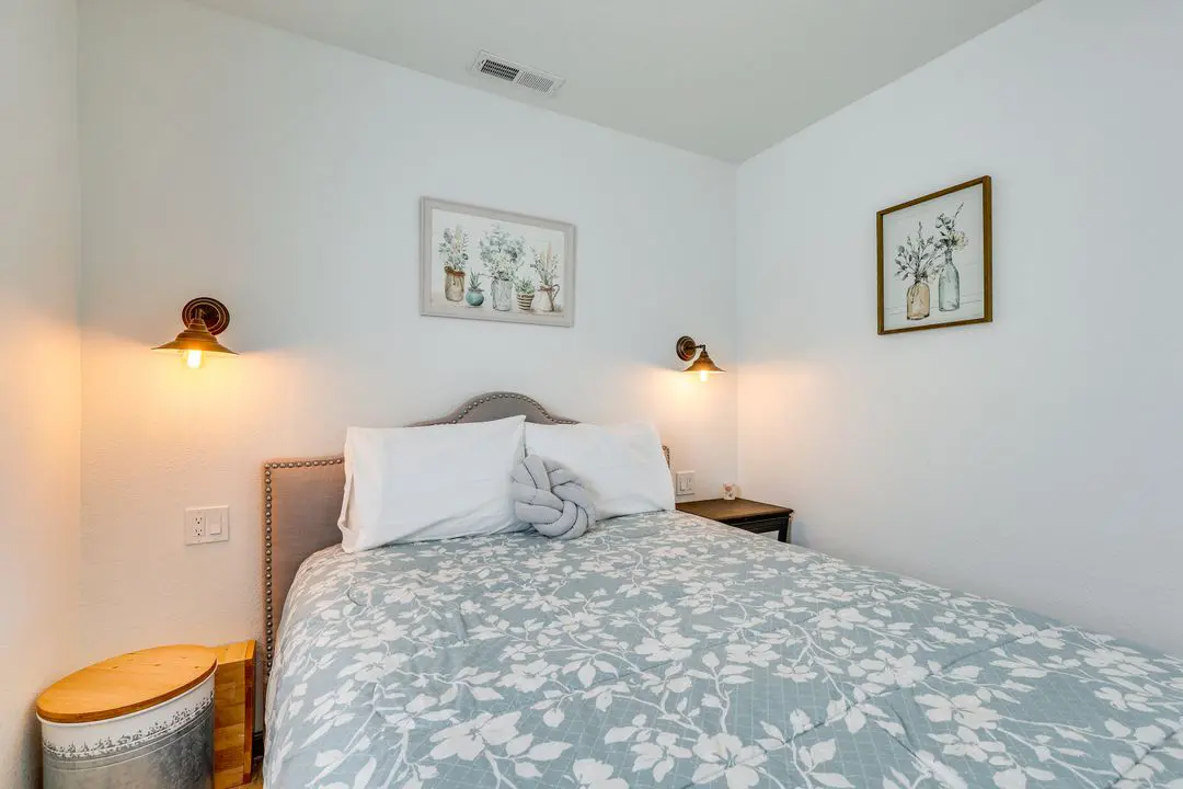 A bed room with a neatly made bed and two lamps