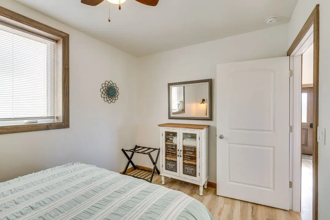 A bedroom with white walls and wooden floors.