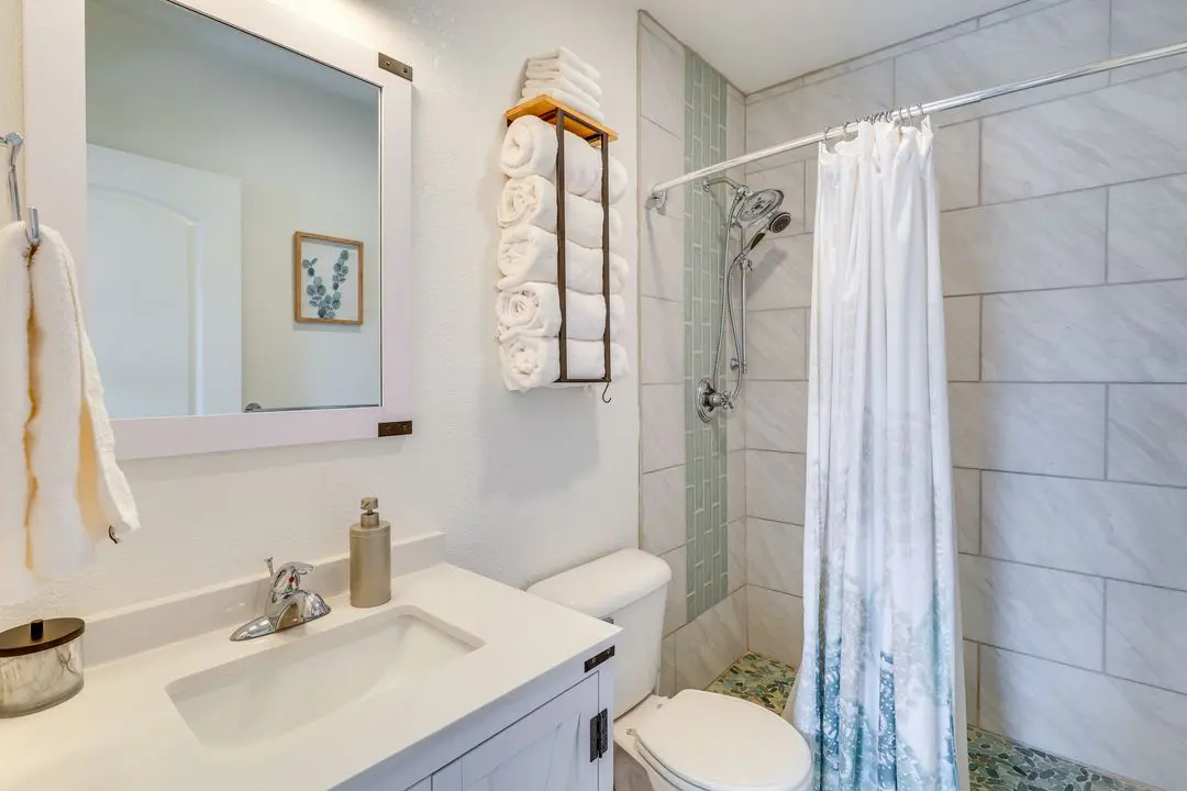 A bathroom with white tile and a shower curtain.